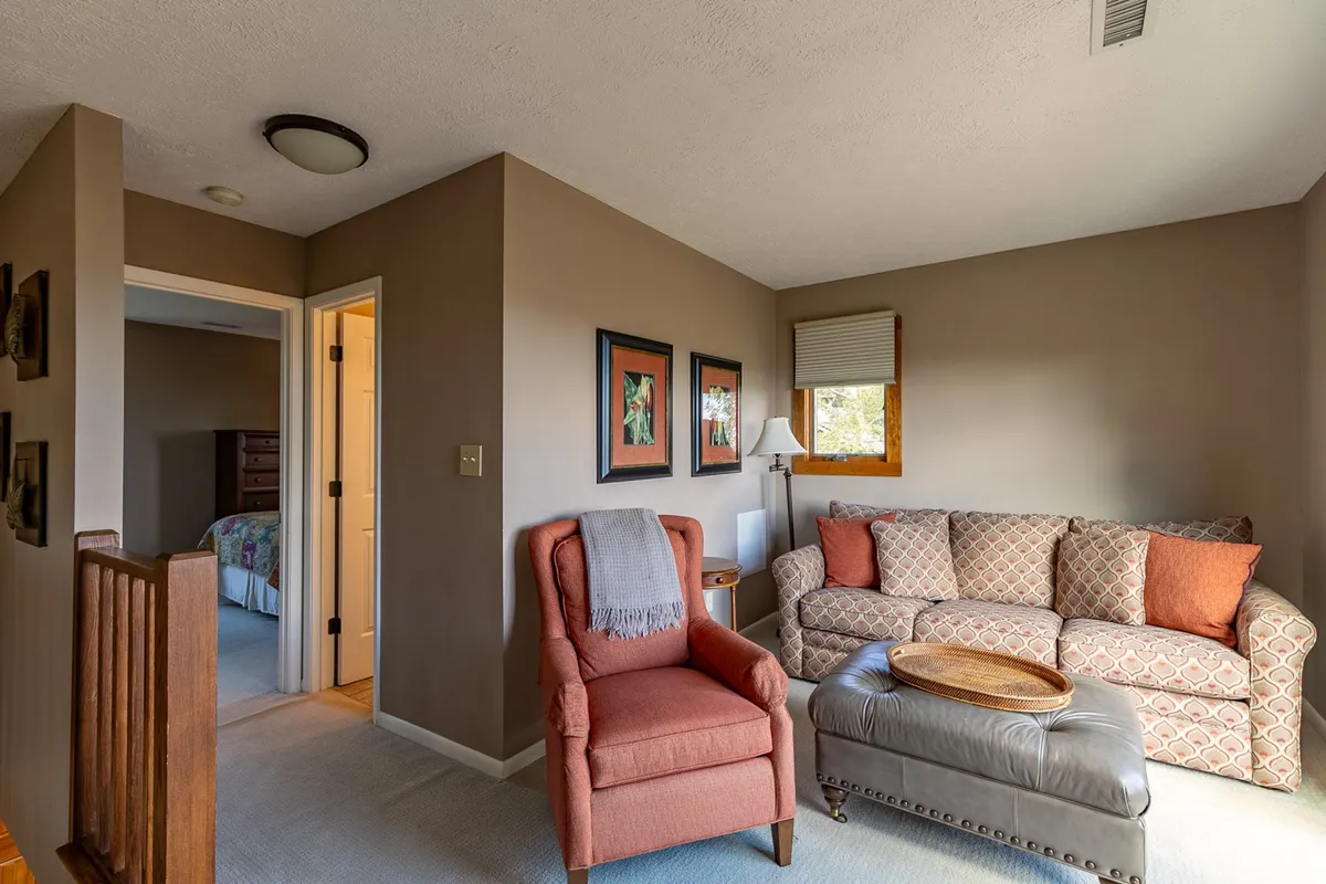 A welcoming living area featuring a textured couch, accent chair, and decorative artwork. The space is styled for intimate conversations, reading, and relaxing, with warm lighting and tasteful decor that evoke comfort and sociability.