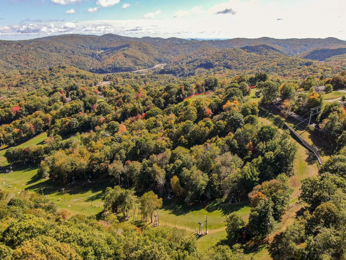 A panoramic view of rolling hills, lush greenery, and distant mountains beneath a clear sky. The scenery evokes a sense of adventure and showcases the natural beauty surrounding the property, ideal for outdoor enthusiasts.